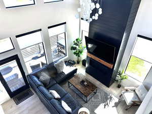 Living area featuring a high ceiling, wood finished floors, healthy amount of natural light, and a chandelier