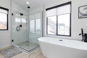 Full bathroom with a freestanding tub, a stall shower, light wood-style flooring, and lofted ceiling