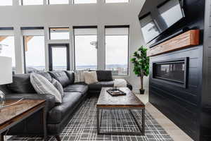 Living room with plenty of natural light, wood finished floors, and a towering ceiling