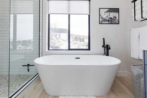 Bathroom with a freestanding tub, a walk in shower, and light wood-style flooring
