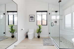 Bathroom featuring lofted ceiling, a stall shower, and light wood finished floors
