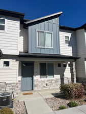 Doorway to property featuring stone siding, covered porch, and board and batten siding