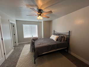 Bedroom featuring a textured ceiling, carpet, and ceiling fan