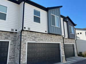 View of property exterior featuring stone siding, an attached garage, and board and batten siding