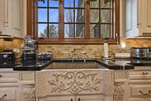 Kitchen featuring decorative backsplash and dark stone countertops