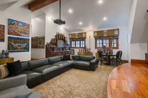 Living area featuring beam ceiling, wood finished floors, a community bar, recessed lighting, and high vaulted ceiling