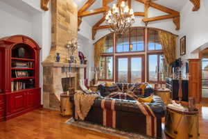 Living room featuring high vaulted ceiling, arched walkways, wood finished floors, a tile fireplace, and beamed ceiling