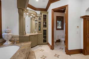 Full bathroom with crown molding, vanity, a bath, decorative columns, and light tile patterned flooring