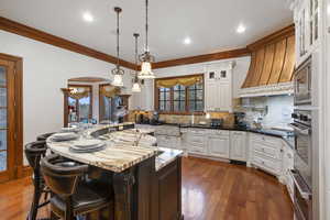 Kitchen with glass insert cabinets, hanging light fixtures, tasteful backsplash, a center island, and a kitchen bar