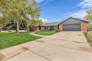 Single story home featuring a front lawn, brick siding, concrete driveway, and an attached garage