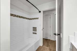 Bathroom featuring washtub / shower combination, wood finished floors, crown molding, and vanity