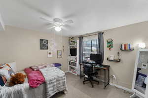Bedroom with light colored carpet, an office area, and ceiling fan