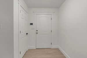 Doorway to outside with wood finished floors and baseboards