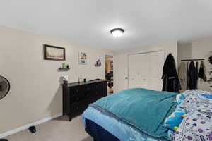 Bedroom featuring light carpet, a closet, and a textured ceiling