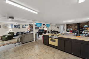 Kitchen featuring open floor plan, a wood stove, light countertops, electric range oven, and a textured ceiling