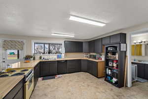 Kitchen with electric range oven, light countertops, dishwasher, a textured ceiling, and stainless steel microwave