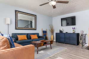 Living area with wood finished floors, a ceiling fan, and a textured ceiling