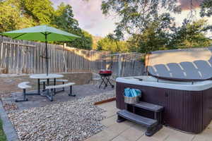 Patio terrace at dusk featuring a hot tub, a patio area, and a fenced backyard