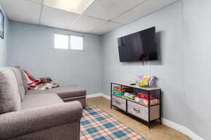 Living room featuring light tile patterned flooring and a drop ceiling
