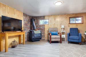 Sitting room featuring a wood stove, wood finished floors, a textured ceiling, and wood walls