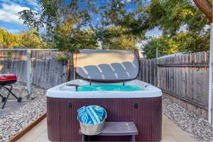 Fenced backyard with a hot tub and a patio