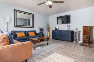 Living room with wood finished floors, ceiling fan, and a textured ceiling
