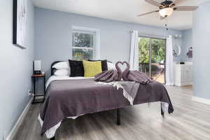 Bedroom with wood finished floors, access to outside, and ceiling fan