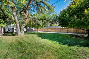 Fenced backyard with view of playhouse, tree swing, and detached garage
