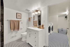 Full bath with vanity, washer and dryer, a textured ceiling, and a shower