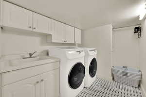 Washroom with cabinet space, independent washer and dryer, and light tile patterned flooring