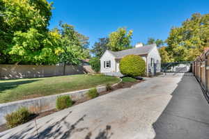 View of home's exterior featuring a chimney, a gate, and concrete driveway