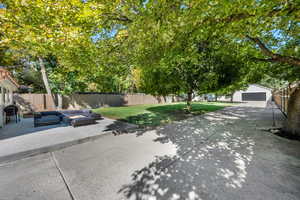 Fenced backyard with outdoor lounge area, a garage, an outbuilding, and a patio