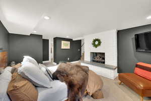 Downstairs living room featuring carpet flooring, a fireplace, recessed lighting, and stairway, used as master suite