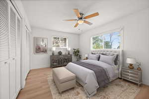 Bedroom featuring two closets, light wood-style flooring, and ceiling fan