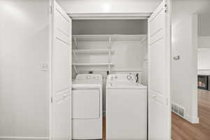 Laundry area featuring washer and dryer, wood finished floors, a barn door, and a lit fireplace