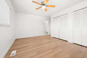 Unfurnished bedroom featuring light wood-style flooring, multiple closets, and ceiling fan