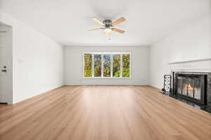 Unfurnished living room with light wood-type flooring, a fireplace with flush hearth, and ceiling fan