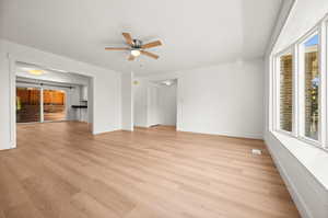Unfurnished living room with plenty of natural light, light wood-style flooring, ceiling fan, and a barn door