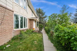 View of exterior entry featuring brick siding and a yard