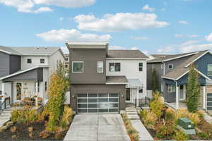 Modern home featuring concrete driveway, an attached garage, a residential view, and roof with shingles