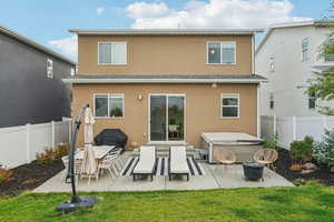 Back of property with a patio, stucco siding, a hot tub, and a fenced backyard