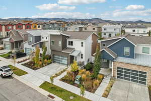 View of front of house with a garage, concrete driveway, stone siding, roof with shingles, and a residential view