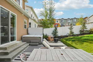 Wooden terrace with a residential view, a hot tub, a fenced backyard, and a patio