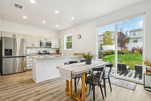 Kitchen featuring appliances with stainless steel finishes, light wood-style flooring, a peninsula, and recessed lighting