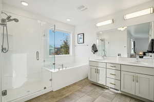 Bathroom with a stall shower, a bath, double vanity, ensuite bath, and light tile patterned floors