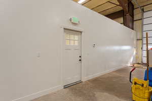 Foyer entrance featuring unfinished concrete flooring and a high ceiling