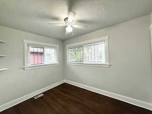 Empty room with dark wood-type flooring and a ceiling fan