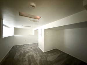 Bonus room featuring dark carpet and baseboards
