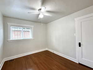 Unfurnished room with dark wood-type flooring and a ceiling fan