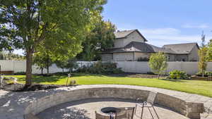 Fenced backyard featuring an outdoor fire pit and a patio